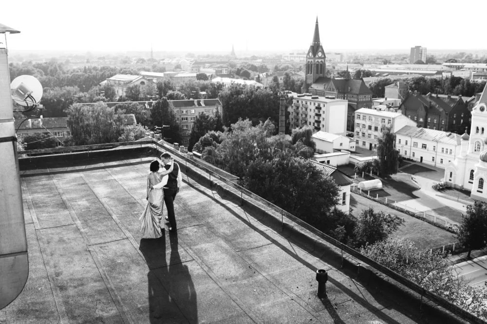 kāzu fotogrāfs fotografē kāzu pāri uz Jelgavas jumta